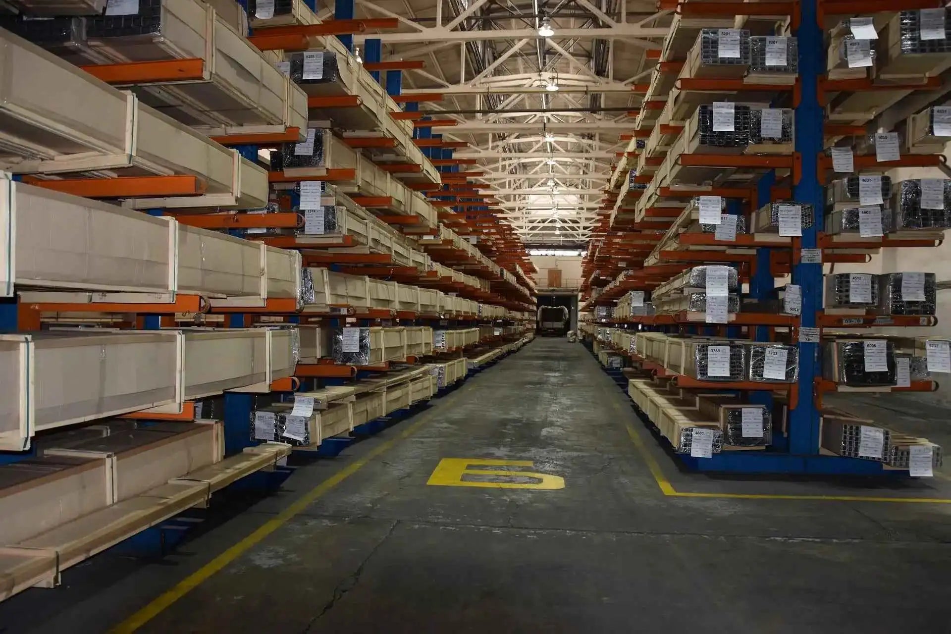 Industrial warehouse with stacked aluminum profiles on metal shelving, organized for storage