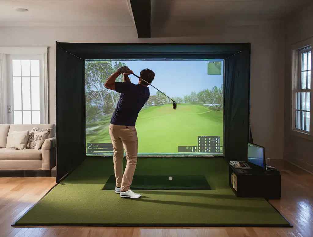 Man using an indoor golf simulator with screen and turf in a modern living room setting